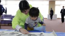 スタッフに見守られながら、子どもが共同作品へ手形スタンプを押す様子