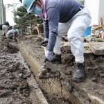 隊員たちは、側溝の汚泥をスコップで懸命に取り除いた(2015年9月21日、茨城県常総市の玉小学校で)"